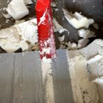 La pelle d'angle retire la mousse du bac acier.